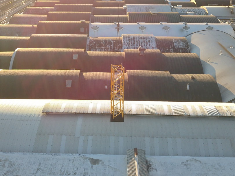 Grove GMK7450 all-terrain crane assembles Potain tower crane for roof replacement at Italian tomato processing plant